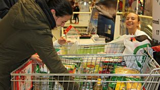 Eine Frau packt Lebensmittel in den Einkaufswagen