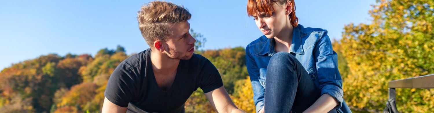 Ein junger Mann mit einem Verbandskasten und eine junge Frau in einer Waldlandschaft