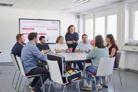 Menschen sitzen am Tisch und lernen Erste Hilfe