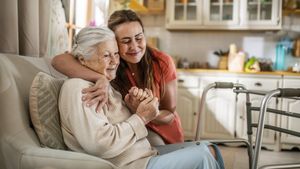 Eine junge Frau umarmt eine ältere Frau auf dem Sofa