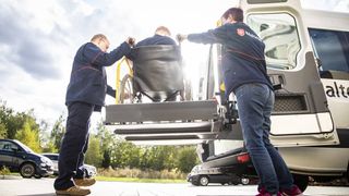 Zwei Mitarbeitende des Malteser Fahrdienstes helfen einer Person im Rollstuhl.