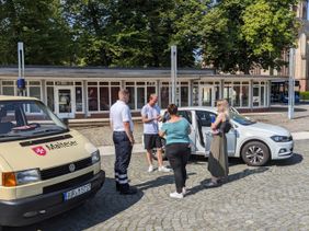 Redakteure von Radio Nordseewelle vor einem Fahrzeug der Malteser Aurich