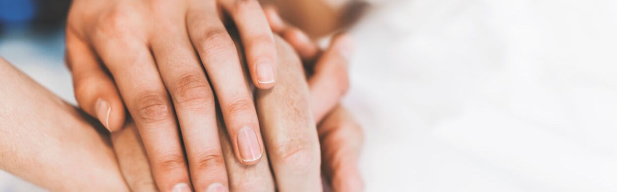 Junge und alte Hände halten zusammen