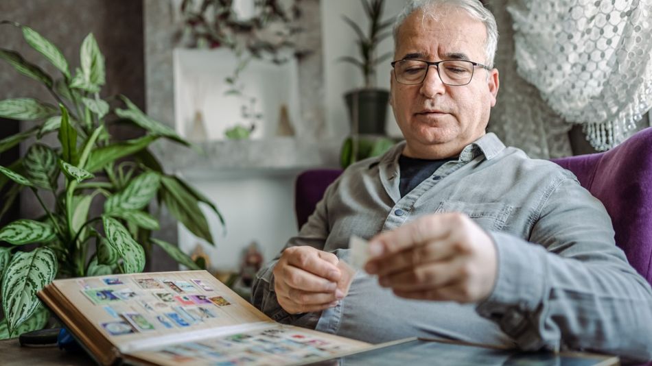 Ein älterer Mann sortiert seine Briefmarkensammlung.