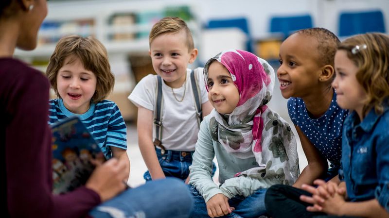 Eine Frau liest Kindern aus einem Buch vor.