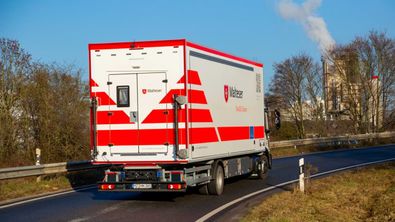 Die Rückansicht eines Malteser LKW der über eine Landstraße fährt.