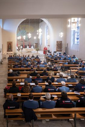 Menschen sitzen in einer Kirche bei einem Gottesdienst vor dem Altar.