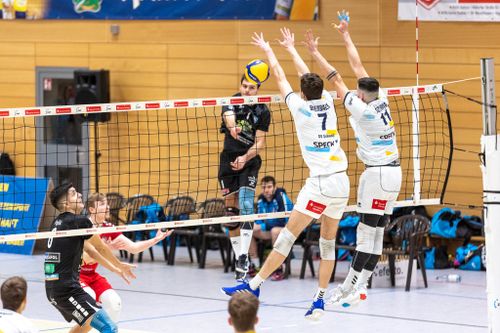 Zwei Spieler des SV Schwaig springen zum Block am Netz, während ein gegnerischer Spieler im schwarzen Trikot angreift.