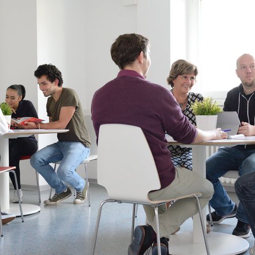 Seminarteilnehmende im Malteser Bildungszentrum sitzen in Gruppen an Tischen und diskutieren.