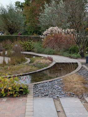 Ein kreisförmiger Weg mit Teichelementen und herbstlichen Gräsern