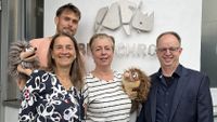 Vier Personen stehen mit zwei Igel Handpuppen vor dem Eingang der Firma Betz Chrom und lächeln in die Kamera.