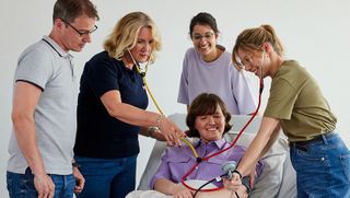 Schüler eines Ausbildungskurses üben am Krankenbett das Blutdruckmessen.