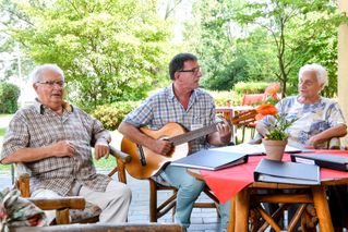 Begleiter des sozialen Dienst spielt für die Bewohner Gitarre und alle singen zusammen
