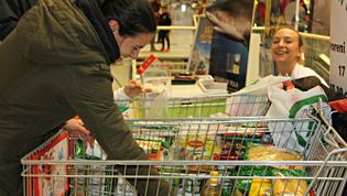Eine Frau packt Lebensmittel in den Einkaufswagen