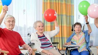 Ältere Menschen halten einen Luftballon in die Luft.