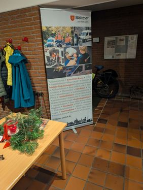 Das Roll-Up der Malteser Aurich listet die vor Ort angebotenene Dienste auf, ERste-Hilfe-Ausbildung, Hausnotruf, Fahrdienst, Sanitätsdienste, Mobiler Einkaufswagen, Auslandsdienst und Kulturbegleitdienst