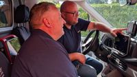 Zwei Männer sitzen gemeinsam in eine Rettungswagen und schauen das eingebaute Einsatztablet an.