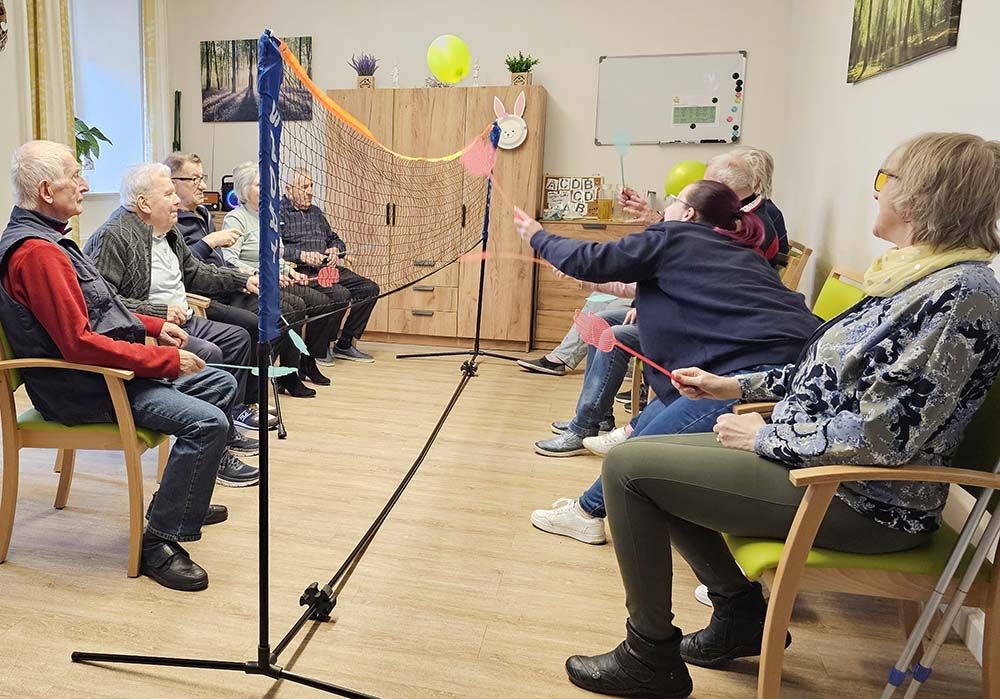 Senioren spielen Federball im Sitzen.