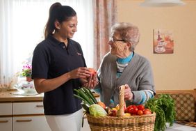 Eine Mitarbeiterin vom ambulanten Pflegedienst der Malteser hilft einer Seniorin bei der Hausarbeit.
