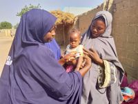 Zwei Frauen aus Nigeria halten einen Jungen