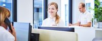 Frau mit Headset sitzt vor dem Computer.