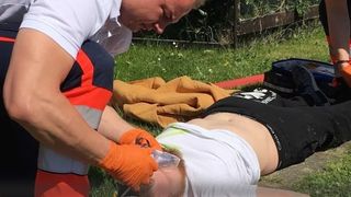 Malteser behandelt einen Verletzten auf einer Wiese