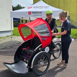 Eine Frau erklärt einer andere Frau, wie eine Fahrrad-Rikscha funktioniert.