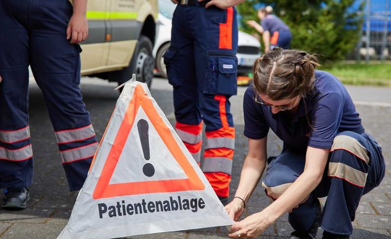 Eine junge Frau in Uniform stellt ein Warnschild mit der Aufschrift „Patientenablage“ auf.