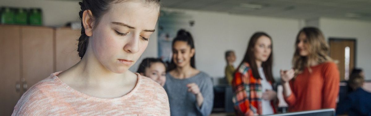 Junges Mädchen wird von Klassenkameradinnen beobachtet