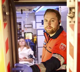 Ein Notarztsanitäter im Krankenwagen - eine Patientin dahinter