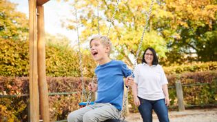 Ein kleiner Junge wird von einer Frau geschaukelt.