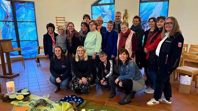 Eine Gruppe von Menschen steht in einem kirchlich gewidmeten Raum.