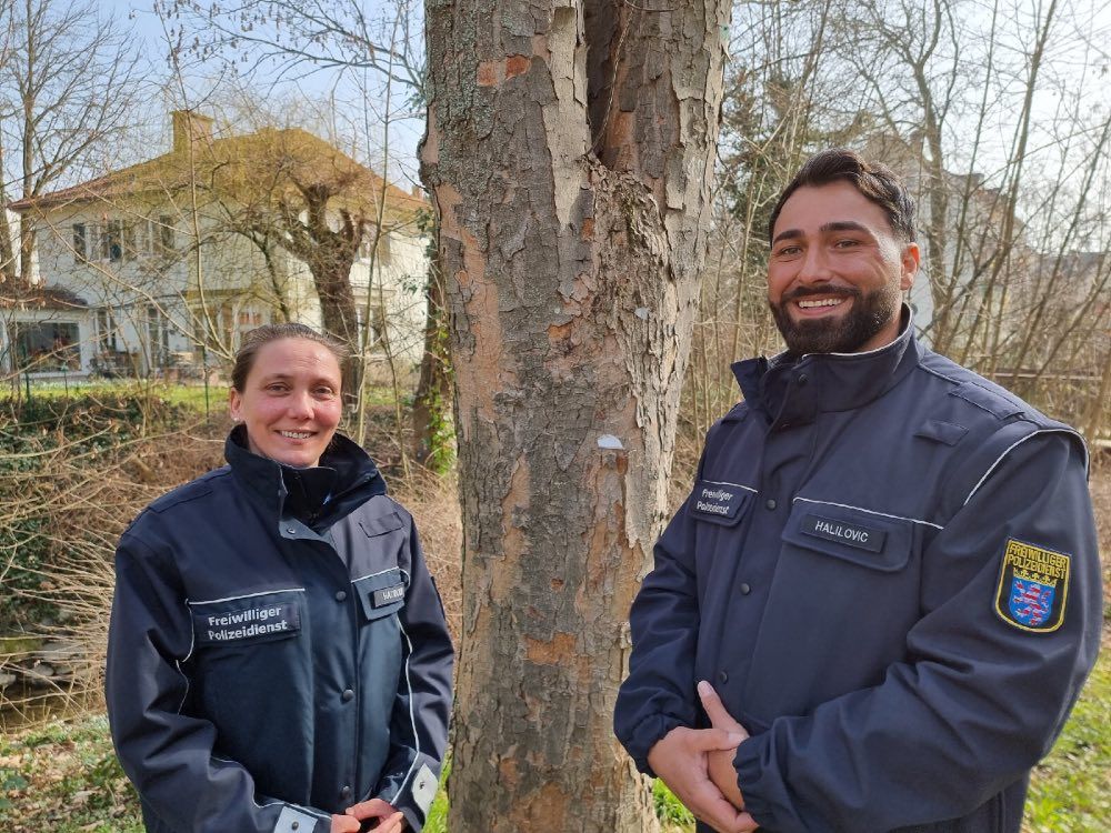 Ein Mann und eine Frau in Uniformen des Freiwilligen Polizeidienstes lächeln in die Kamera.