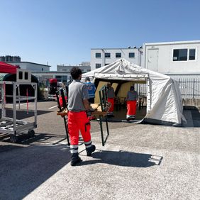 Helfer trägt Tische in die Verpflegungsstelle