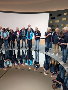 Die Ehrenamtlichen stehen dicht am Spiegel und bewundern den Blick in den Himmel zu ihren Füßen