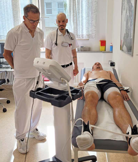 Zwei Ärzte überwachen eine Untersuchung bei einem Patienten, der mit Sensoren auf einer Liege liegt.