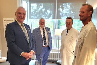 Vier Männer stehen im Halbkreis in einem Zimmer.