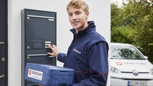 Junger Mann mit Warmhaltebox klingelt an einer Haustür.
