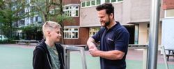 Ein Mann spricht auf einem Schulhof mit einem Jungen.