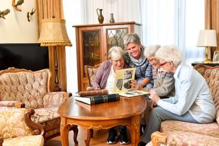 Vier Frauen sitzen auf dem Sofa und schauen sich gemeinsam ein Fotoalbum an