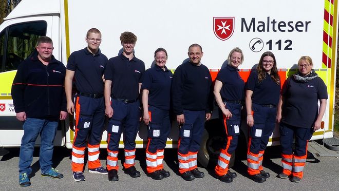 Gruppenbild der neuen Rettungssanitäter mit dem Leiter Einsatzdienste und der Gliederungsärztin vor einem Rettungswagen 