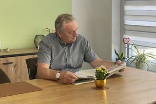 Ein Senior mit einem Hausnotruf-Armband beim Zeitunglesen