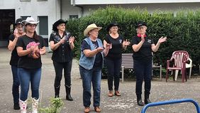 Mehrere Frauen mit Cowboy-Hüten tanzen.