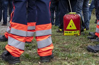 Beine in Einsatzhose im Vordergrund mit Sanitätsrucksack im Hintergrund