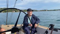 Älterer Mann sitzt am Steuer eines Segelbootes am Starnberger See.