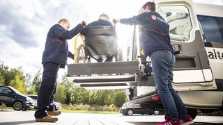 Zwei Mitarbeitende des Malteser Fahrdienstes helfen einer Person im Rollstuhl.