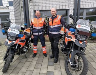 2 Männer stehen in Malteser Motorradkleidung vor der Malteser Dienststelle in Rülzheim