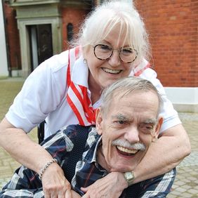 Eine Frau umarmt einen Mann im Rollstuhl.