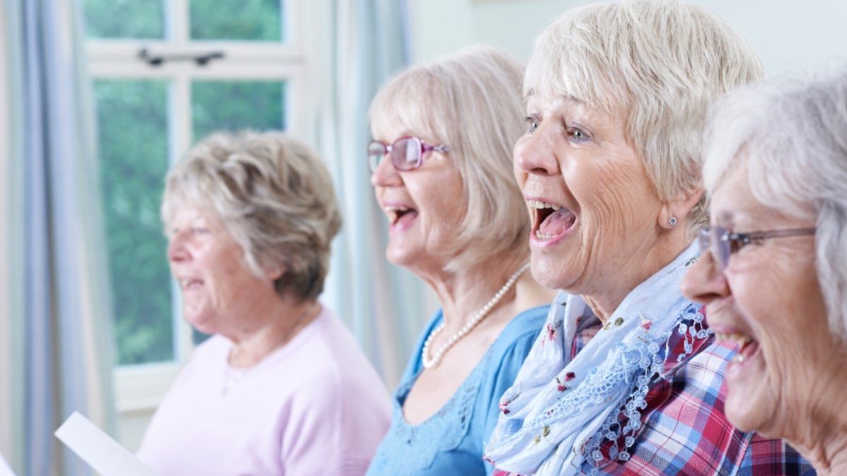 Vier ältere Frauen mit Notenblättern in der Hand singen