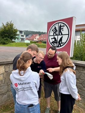Fünf ehrenamtliche Malteser schauen gemeinsam auf eine Karte.